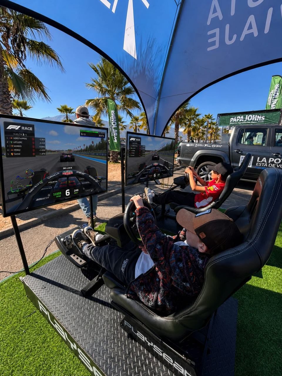 Niños compitiendo en simuladores de carreras F1 en evento al aire libre para Salazar Israel