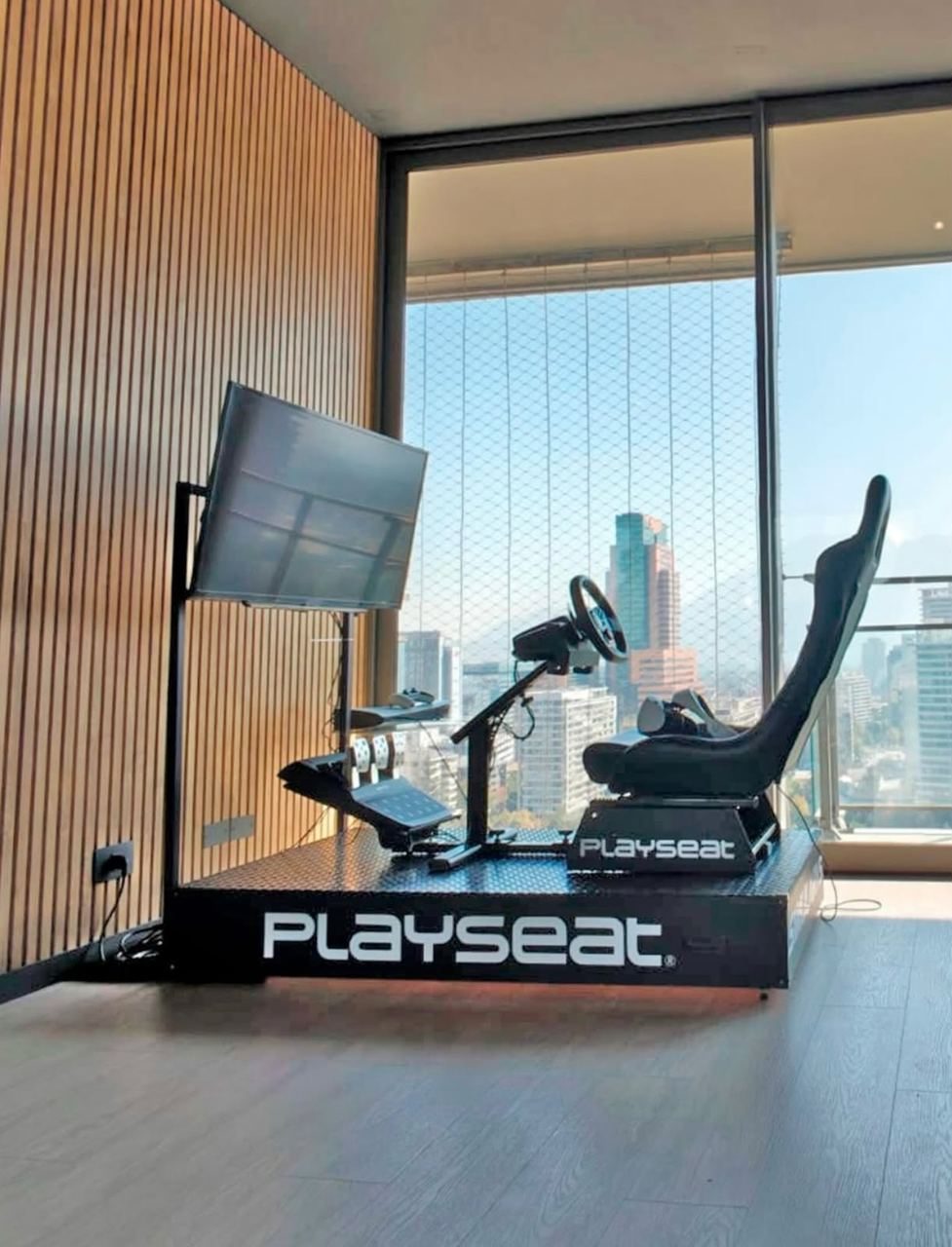Simulador de carreras Playseat instalado en departamento con vista panorámica de Santiago para Xiaomi